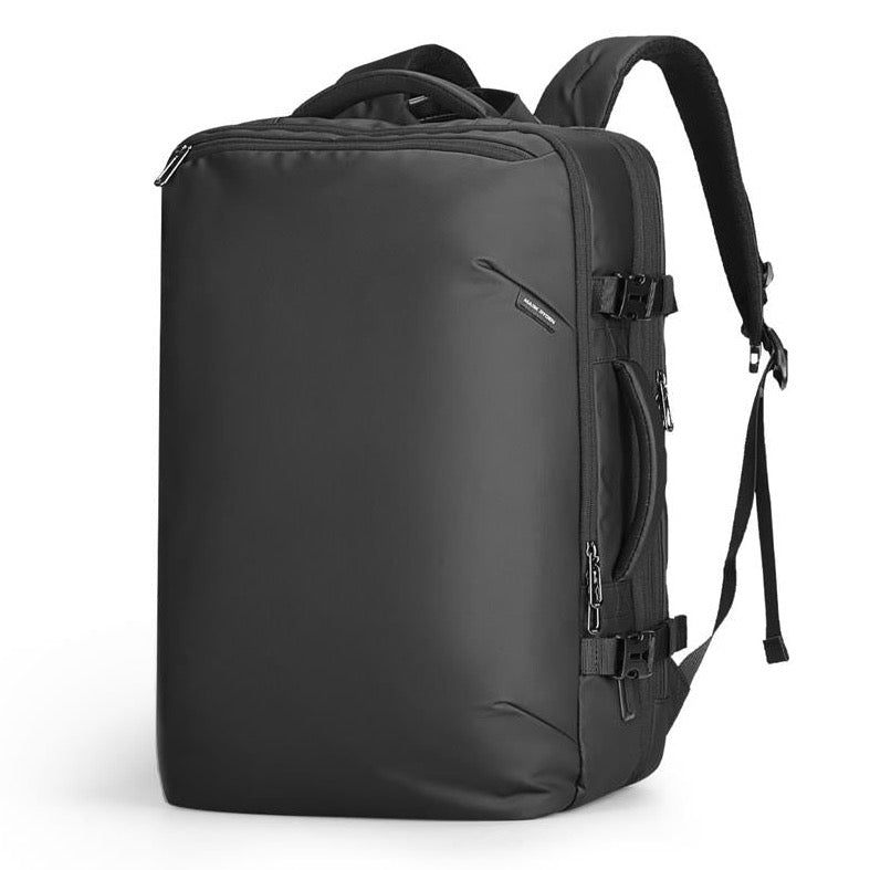 Nomad expandable laptop travel backpack in black and grey, featuring separate compartments for 17.3" laptop and iPad, wet/dry pocket, side water bottle pocket, and anti-theft back pocket for secure storage.