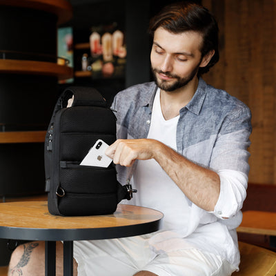 Man with Mark Ryden Crypto usb charging waterproof sling bag in black. 